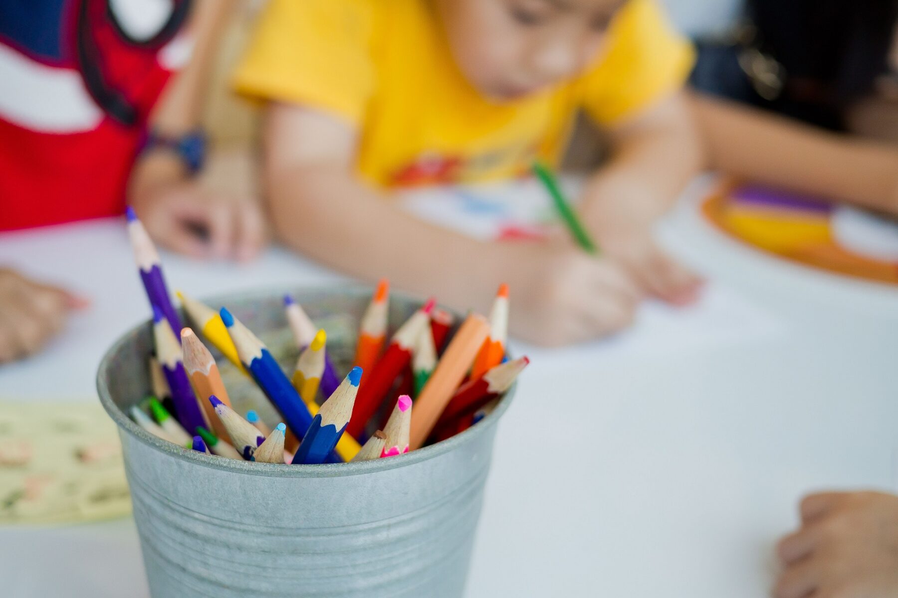 kids coloring and a container full of crayons